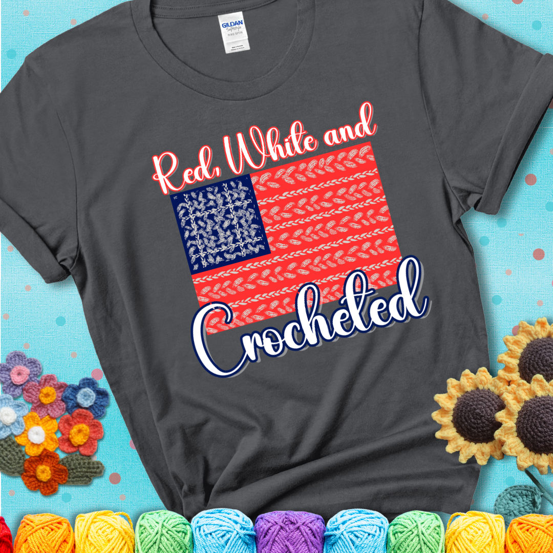 Charcoal grey t-shirt showing a patriotic crochet-themed American flag design with red and white yarn stitches forming the stripes and blue and white stitches as stars.