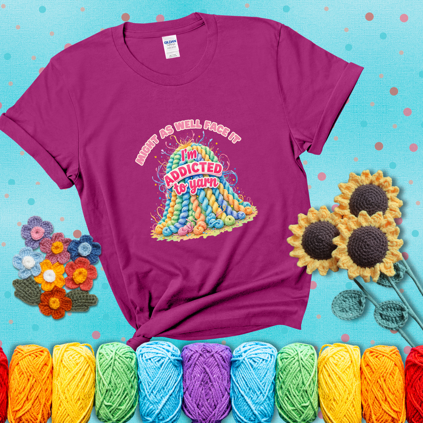 Colorful mountain of pastel yarn hanks with the phrase “Might as well face it, I’m addicted to yarn” in playful pink and red lettering showing a magenta tee with a teal sunflower background