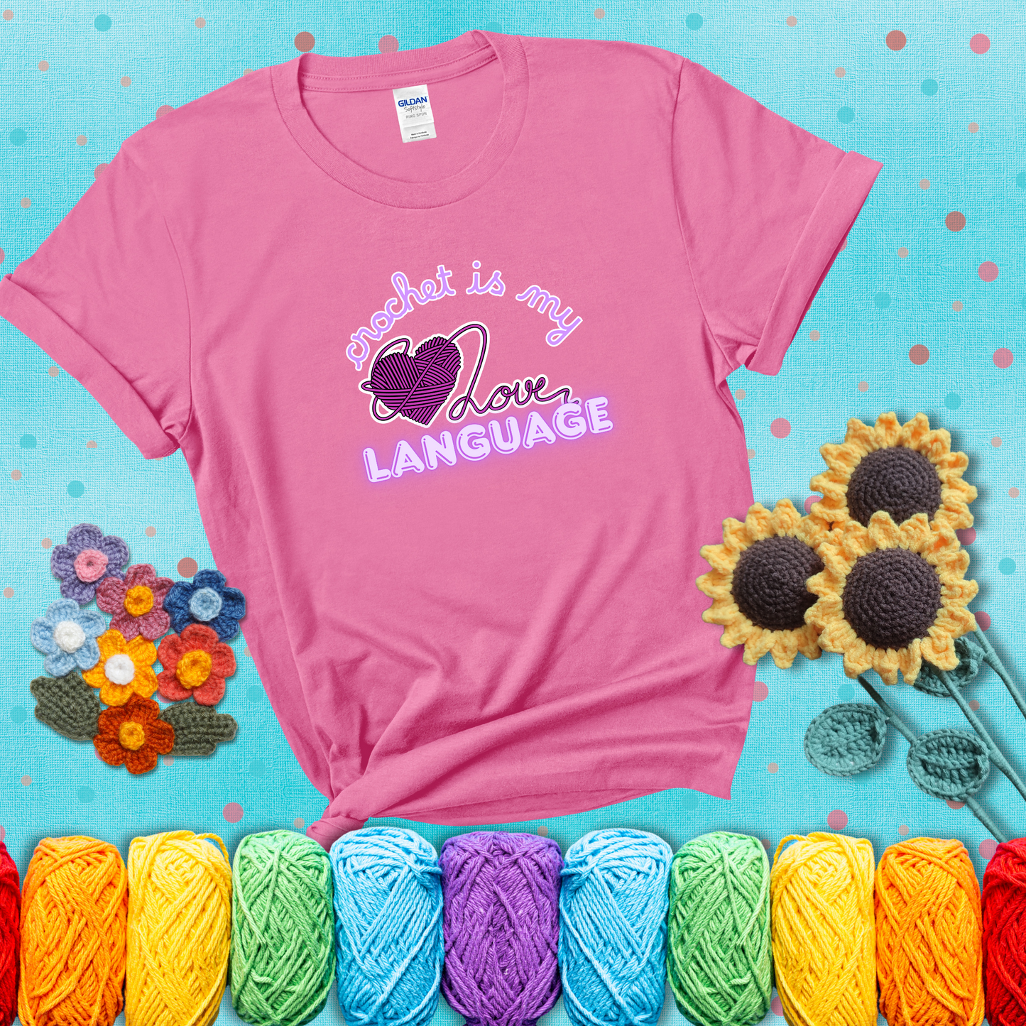 Say it with stitches Design reads 'Crochet Is My Love Language', perfect crochet gift for yarn lovers; showing a pink tee with a teal sunflower background