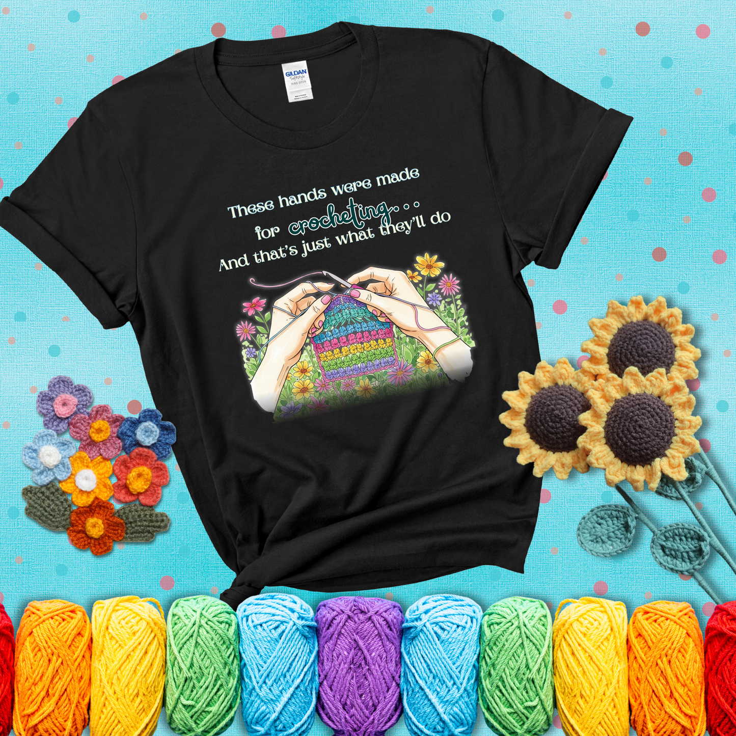 Illustration of two hands crocheting a rainbow swatch, surrounded by vibrant flowers with the phrase “These hands were made for crocheting… and that’s just what they’ll do,” showing a black tee with a teal sunflower background