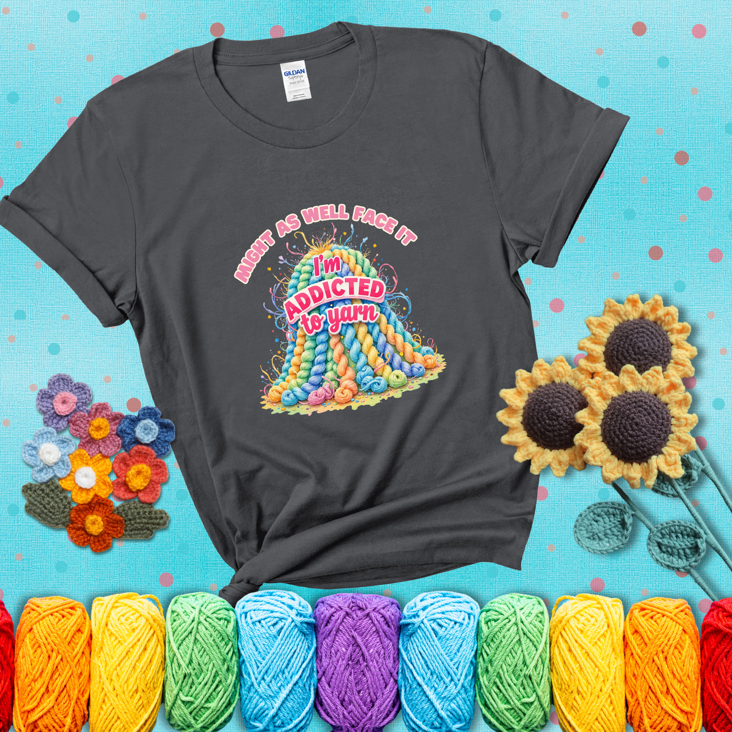 Colorful mountain of pastel yarn hanks with the phrase “Might as well face it, I’m addicted to yarn” in playful pink and red lettering showing a dark grey tee with a teal sunflower background