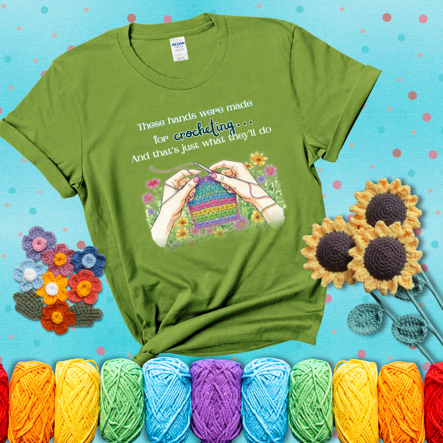 Illustration of two hands crocheting a rainbow swatch, surrounded by vibrant flowers with the phrase “These hands were made for crocheting… and that’s just what they’ll do,” showing a bright green tee with a teal sunflower background