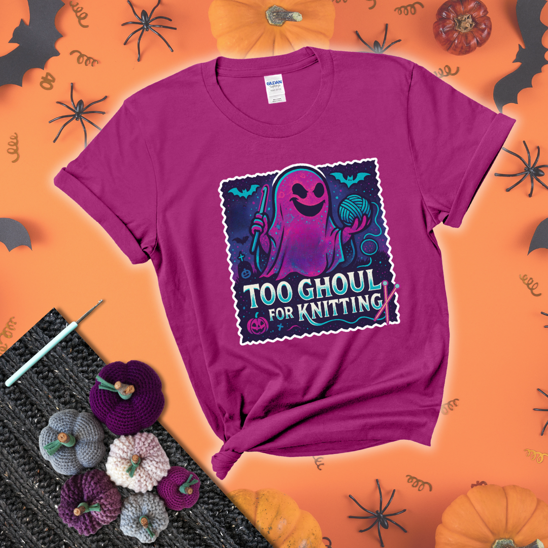 A spooky ghost holds a yarn ball and crochet hook in a vibrant Halloween palette with bats, tombstones, and pumpkins wearing a magenta tee with a festive halloween background