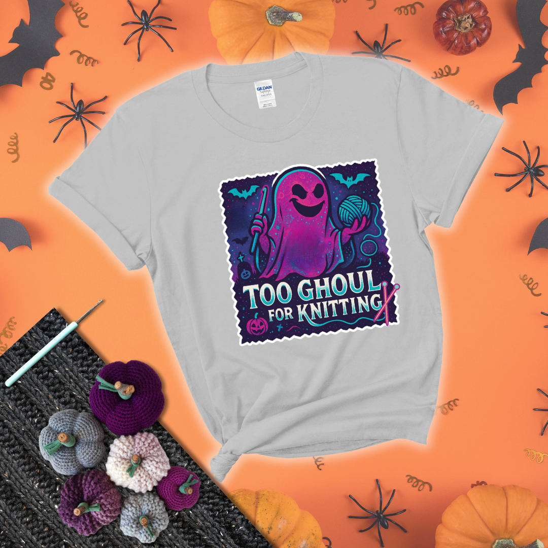 A spooky ghost holds a yarn ball and crochet hook in a vibrant Halloween palette with bats, tombstones, and pumpkins wearing a light grey tee with a festive halloween background