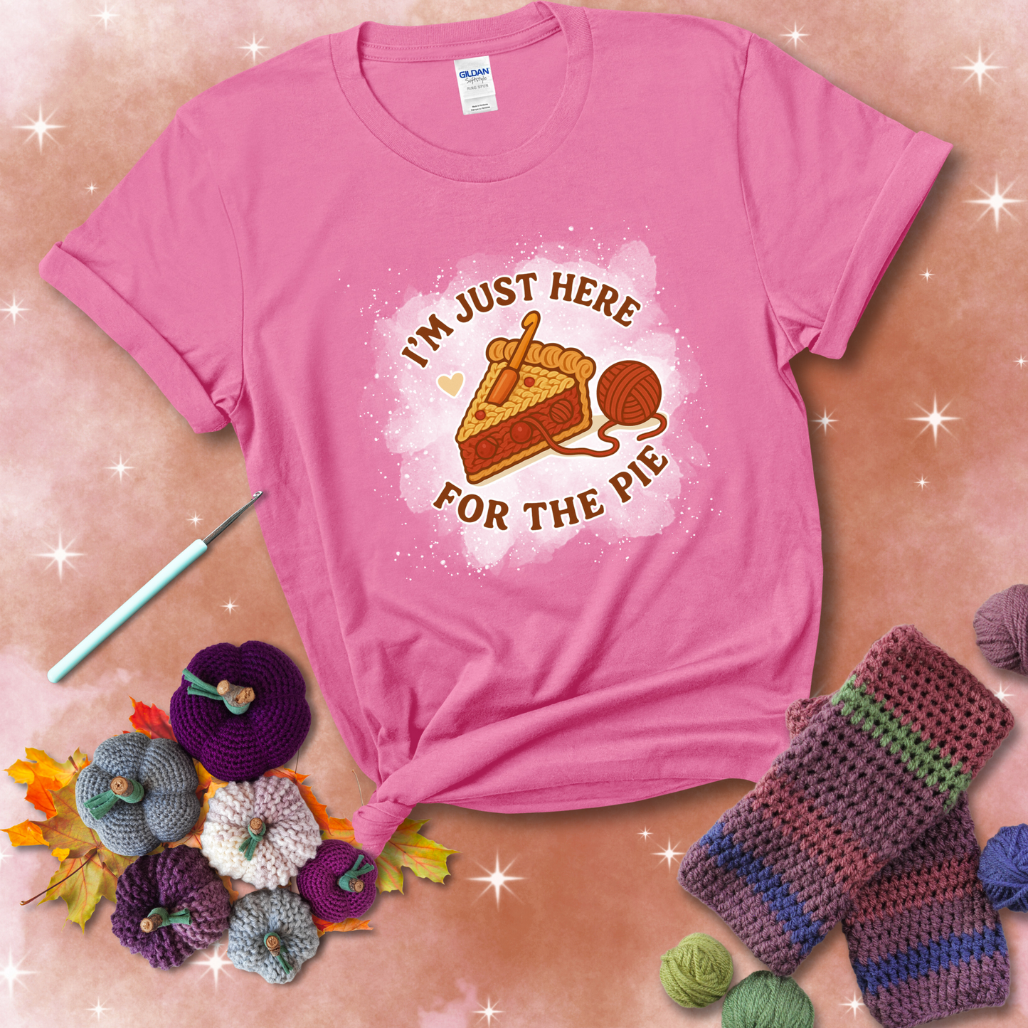 A slice of cherry pie with a crochet hook tucked in the filling and yarn trailing out, blending baking with crochet fun, showing a pink tee with a festive Fall background