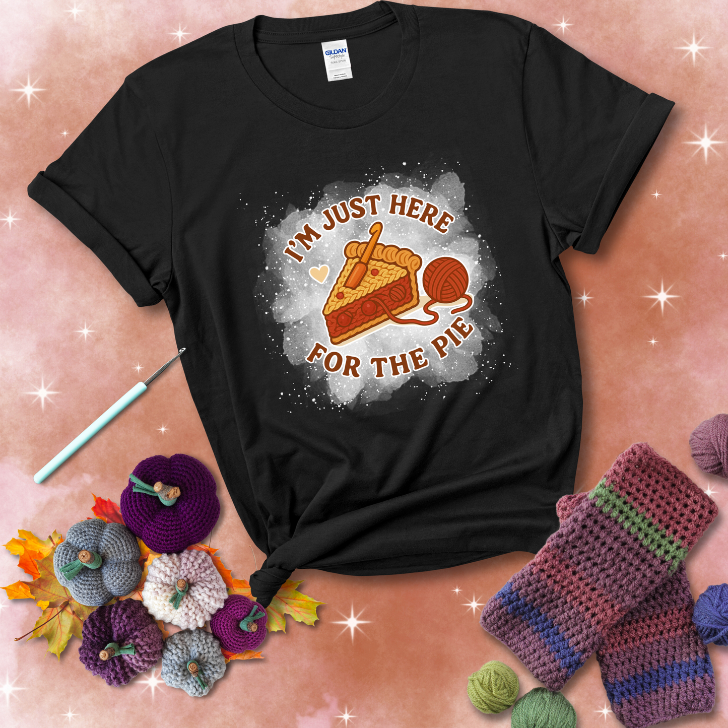 A slice of cherry pie with a crochet hook tucked in the filling and yarn trailing out, blending baking with crochet fun, showing a black tee with a festive Fall background