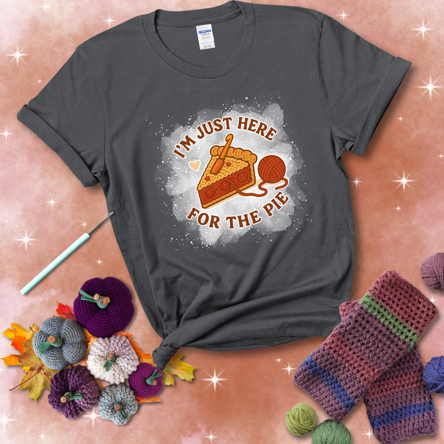 A slice of cherry pie with a crochet hook tucked in the filling and yarn trailing out, blending baking with crochet fun, showing a dark grey tee with a festive Fall background