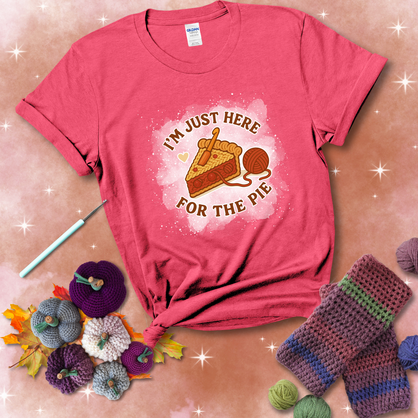 A slice of cherry pie with a crochet hook tucked in the filling and yarn trailing out, blending baking with crochet fun, showing a light red tee with a festive Fall background