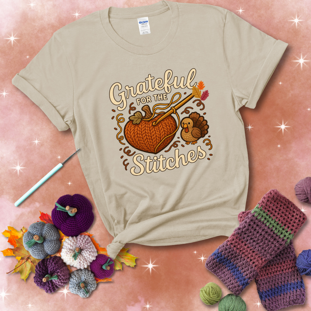 A cozy fall scene with a crochet hook stitching a heart-shaped pumpkin, surrounded by yarn and a small turkey, showing a beige tee with a festive Fall background
