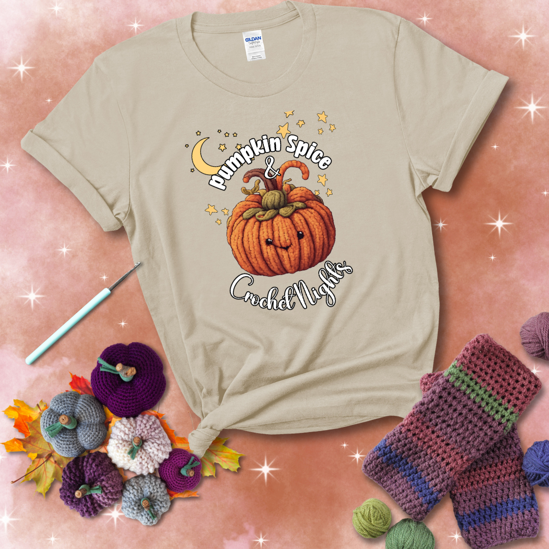 Smiling pumpkin crocheted with yarn texture, surrounded by stars and a crescent moon. Text reads “Pumpkin Spice & Crochet Nights” showing a beige tee with a festive Fall background