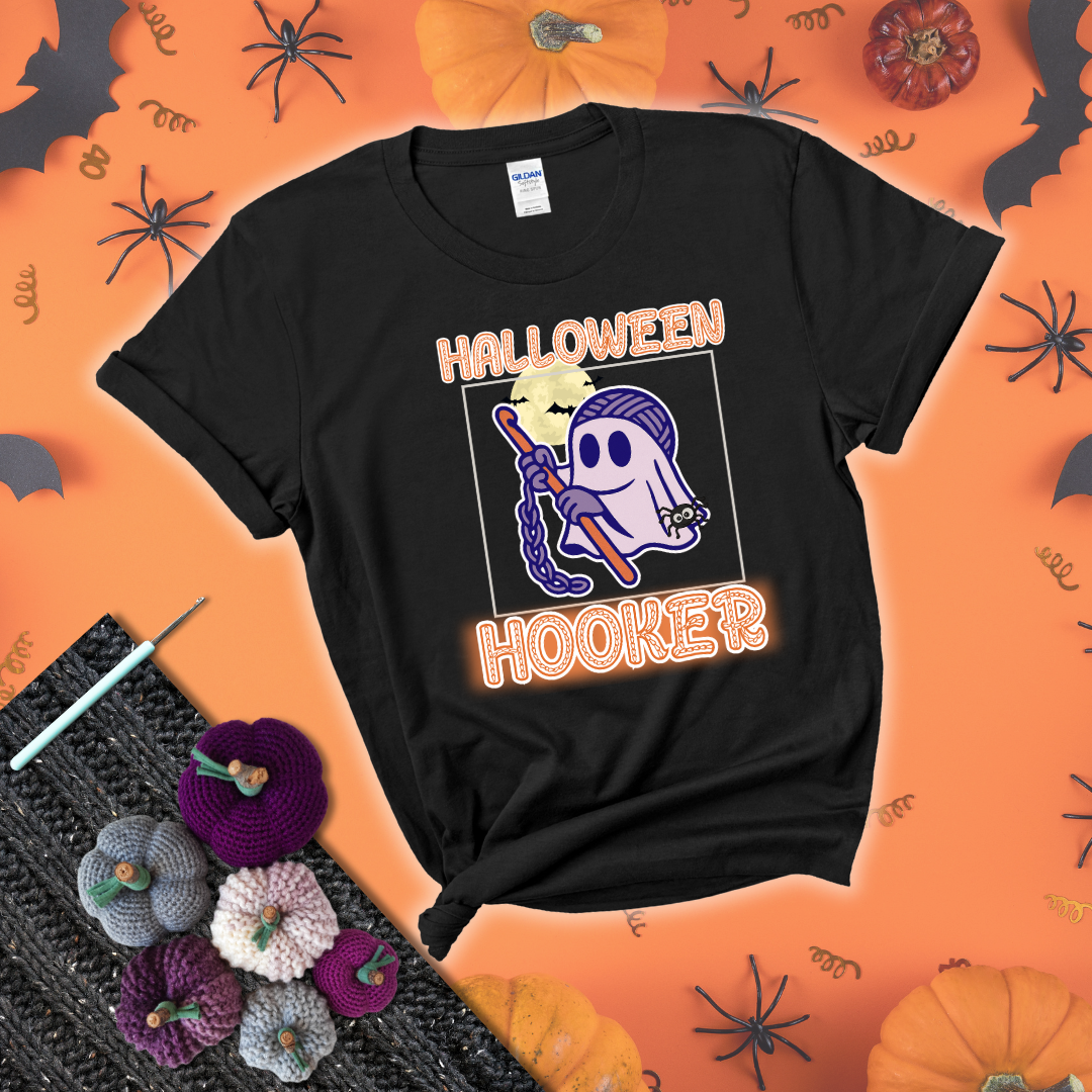 Cartoon ghost crocheter with a yarn ball head, crochet hook, bats, and text “Halloween Hooker,” a fun spooky tee for yarn lovers showing a black tee with a festive Halloween background
