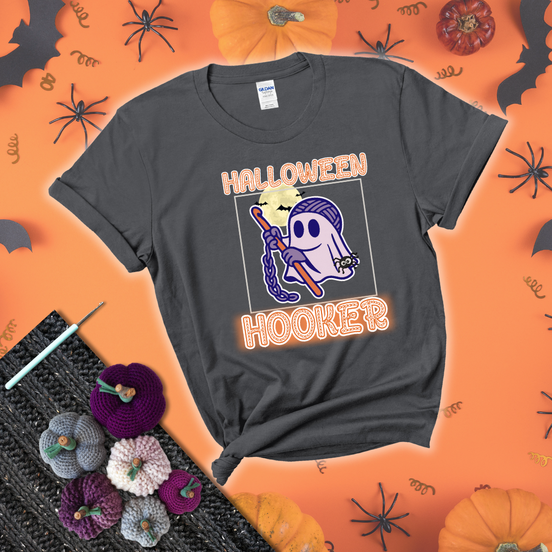 Cartoon ghost crocheter with a yarn ball head, crochet hook, bats, and text “Halloween Hooker,” a fun spooky tee for yarn lovers showing a dark grey tee with a festive Halloween background
