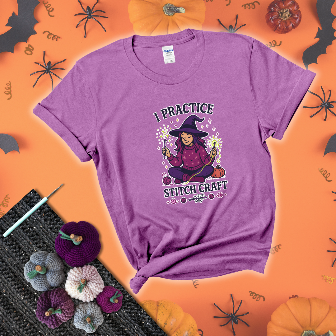 Witchy crocheter sits cross-legged, conjuring yarn magic with crochet hooks and glowing green yarn, surrounded by stars, pumpkins, and stitchy vibes showing a light purple tee with a festive Halloween background