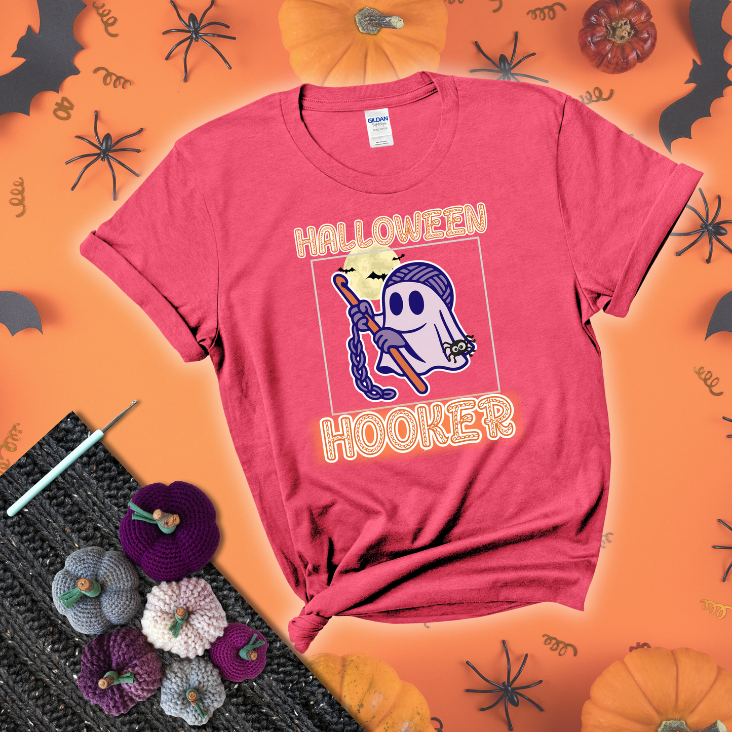 Cartoon ghost crocheter with a yarn ball head, crochet hook, bats, and text “Halloween Hooker,” a fun spooky tee for yarn lovers showing a light red tee with a festive Halloween background