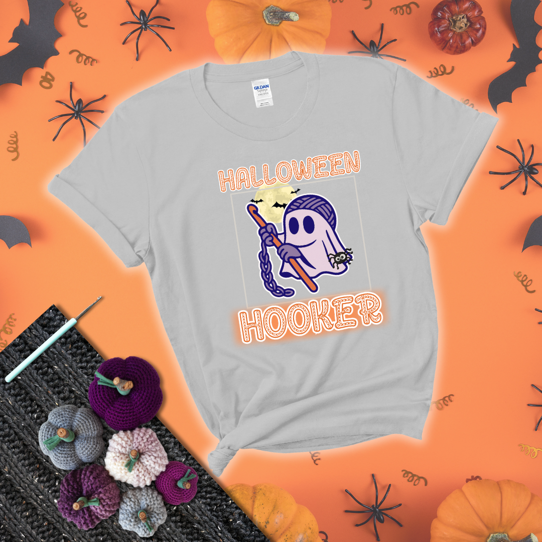 Cartoon ghost crocheter with a yarn ball head, crochet hook, bats, and text “Halloween Hooker,” a fun spooky tee for yarn lovers showing a light grey tee with a festive Halloween background