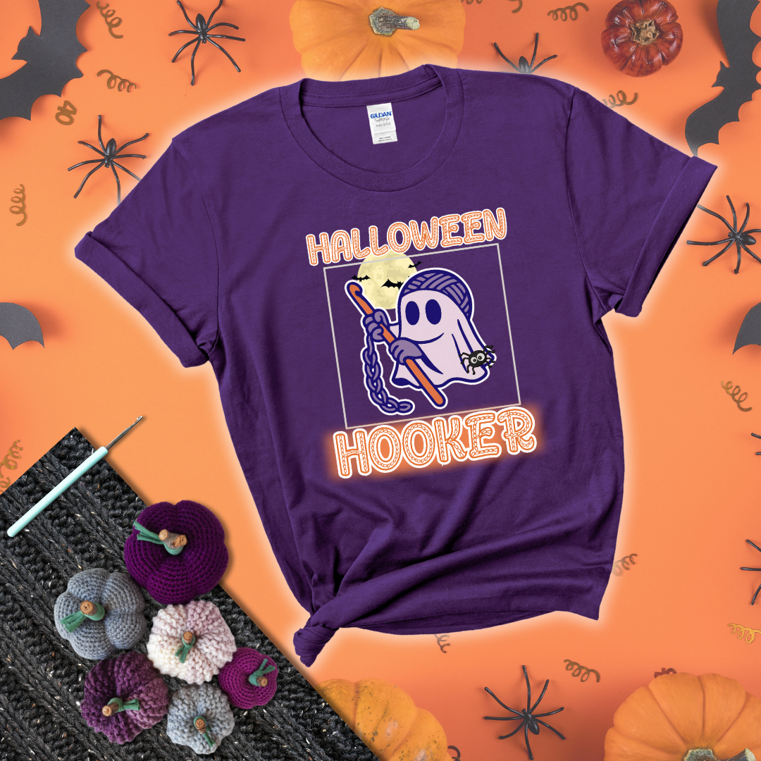 Cartoon ghost crocheter with a yarn ball head, crochet hook, bats, and text “Halloween Hooker,” a fun spooky tee for yarn lovers showing a purple tee with a festive Halloween background