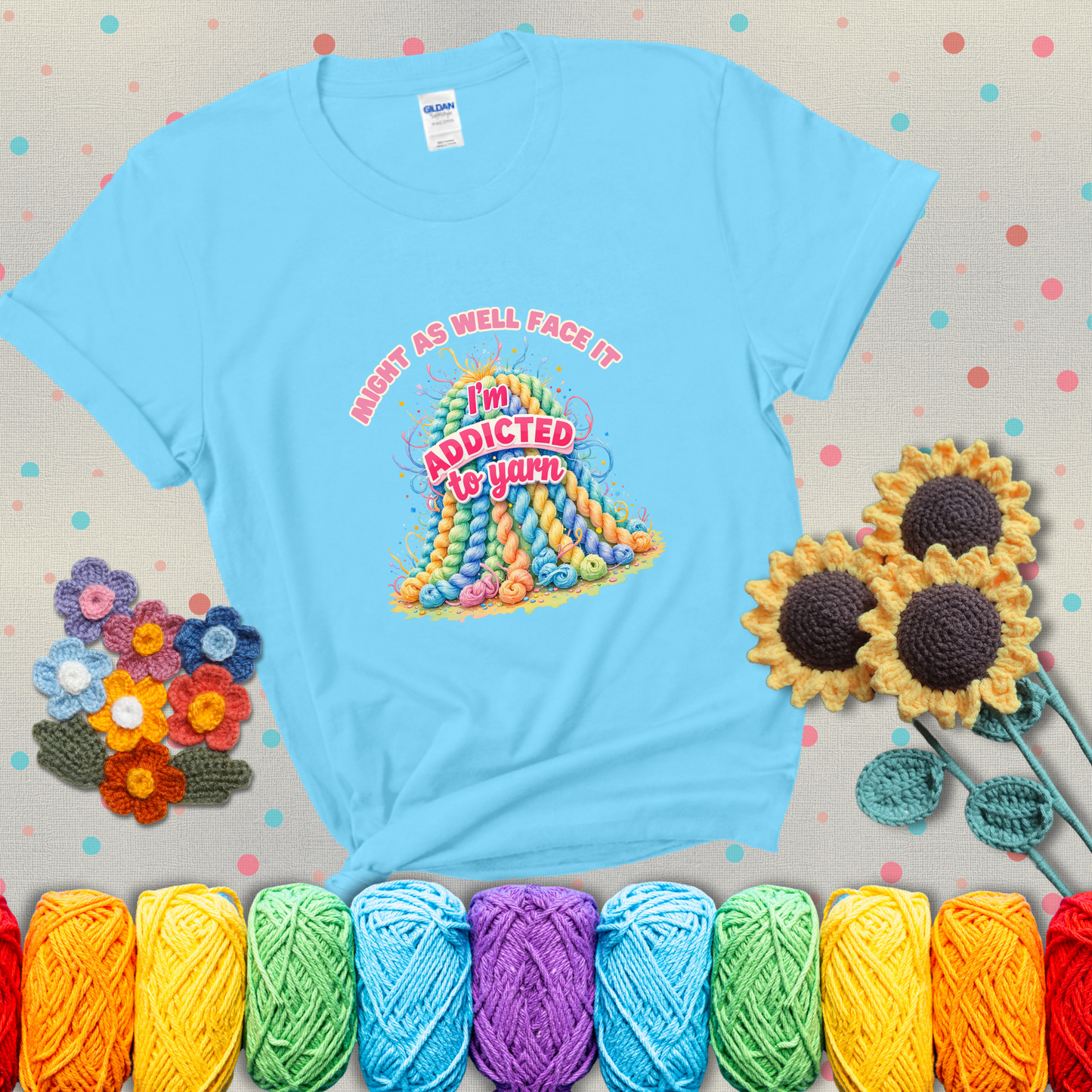 Colorful mountain of pastel yarn hanks with the phrase “Might as well face it, I’m addicted to yarn” in playful pink and red lettering showing a light blue tee with grey sunflower background
