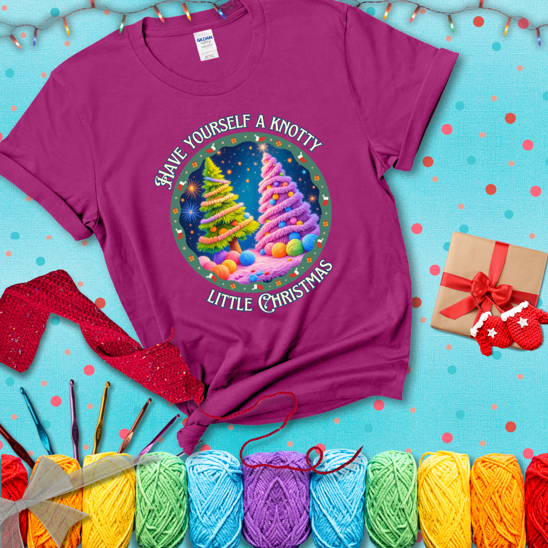 Two yarn-covered Christmas trees wrapped in colorful strands of yarn, with the phrase "Have Yourself a Knotty Little Christmas" encircling the scene showing a magenta tee with a festive Christmas background