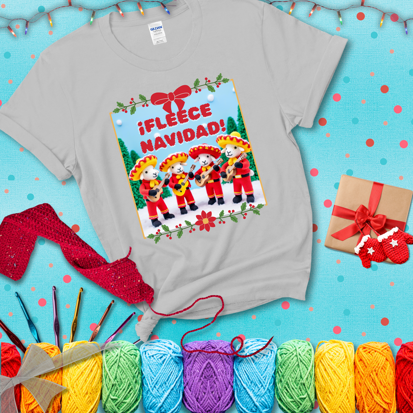 Four crocheted sheep dressed in red mariachi outfits with guitars, standing in a snowy scene under the phrase “¡Fleece Navidad!” showing a light grey tee with a festive Christmas background