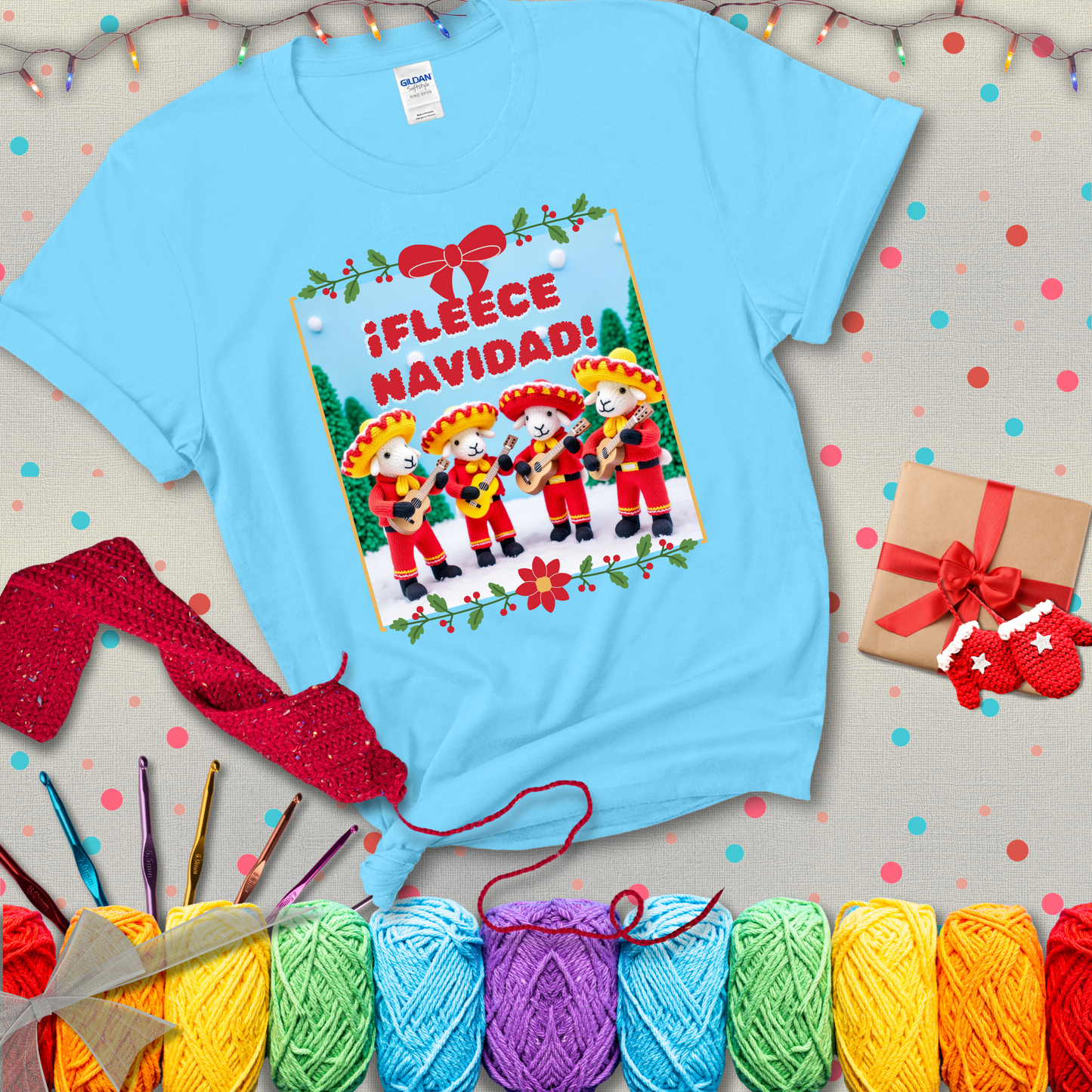 Four crocheted sheep dressed in red mariachi outfits with guitars, standing in a snowy scene under the phrase “¡Fleece Navidad!” showing a light blue tee with a festive Christmas background