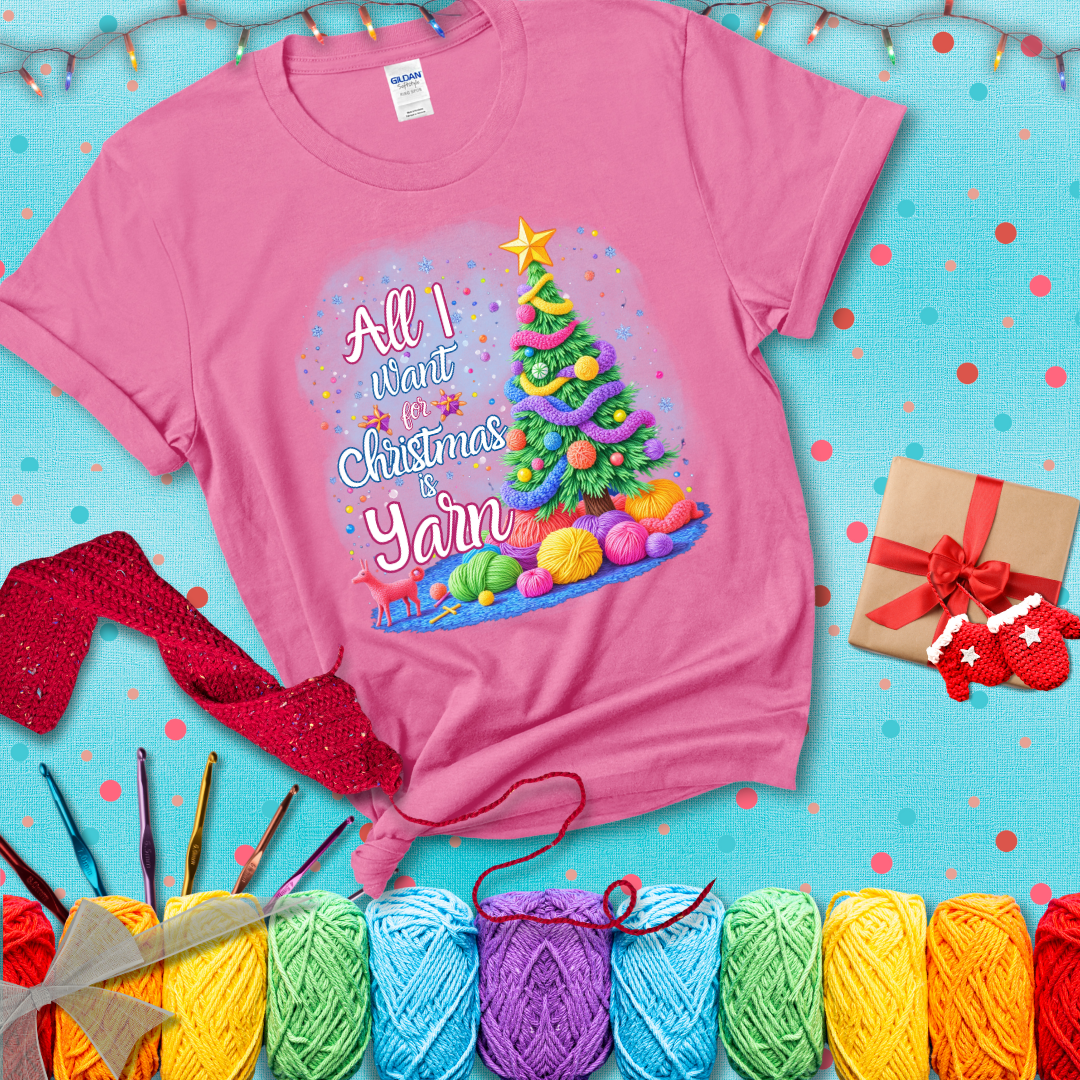 Bright Christmas tree decorated with yarn garlands, balls of yarn underneath, and the text “All I Want for Christmas is Yarn” in festive fonts, showing a pink tee with a festive Christmas background