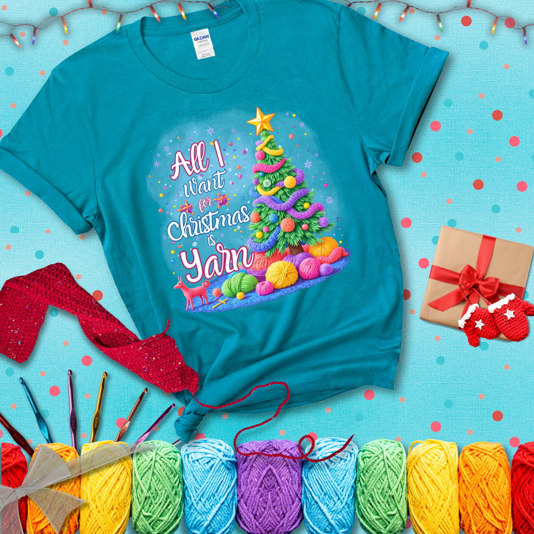 Bright Christmas tree decorated with yarn garlands, balls of yarn underneath, and the text “All I Want for Christmas is Yarn” in festive fonts, showing a blue-green tee with a festive Christmas background