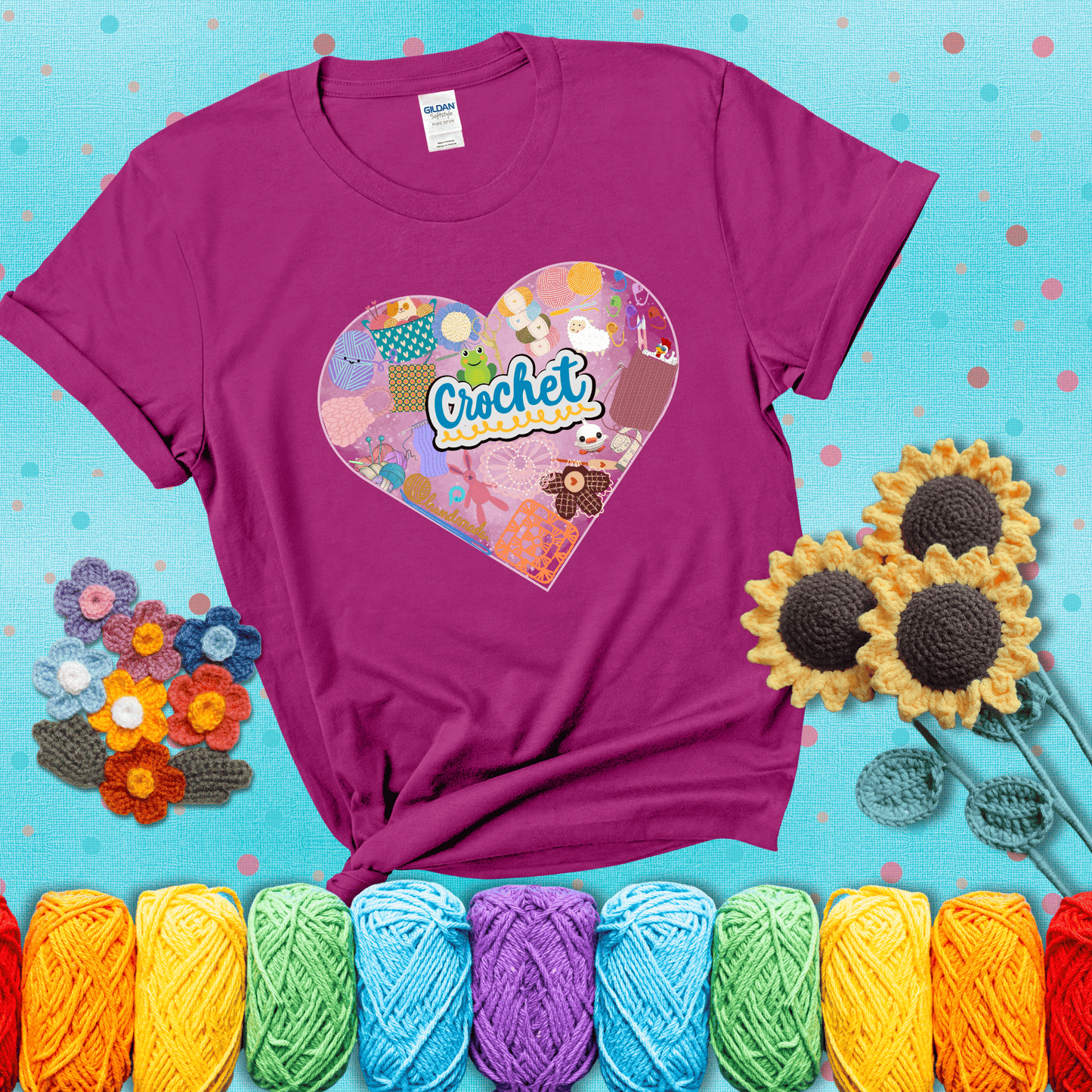 A heart filled with colorful crochet essentials including yarn, hooks, scissors, notions, and handmade items, with the word "Crochet" prominently in the center, showing a magenta tee with a teal sunflower background
