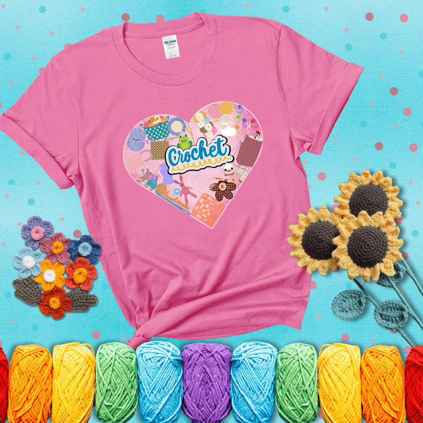 A heart filled with colorful crochet essentials including yarn, hooks, scissors, notions, and handmade items, with the word "Crochet" prominently in the center, showing a pink tee with a teal sunflower background
