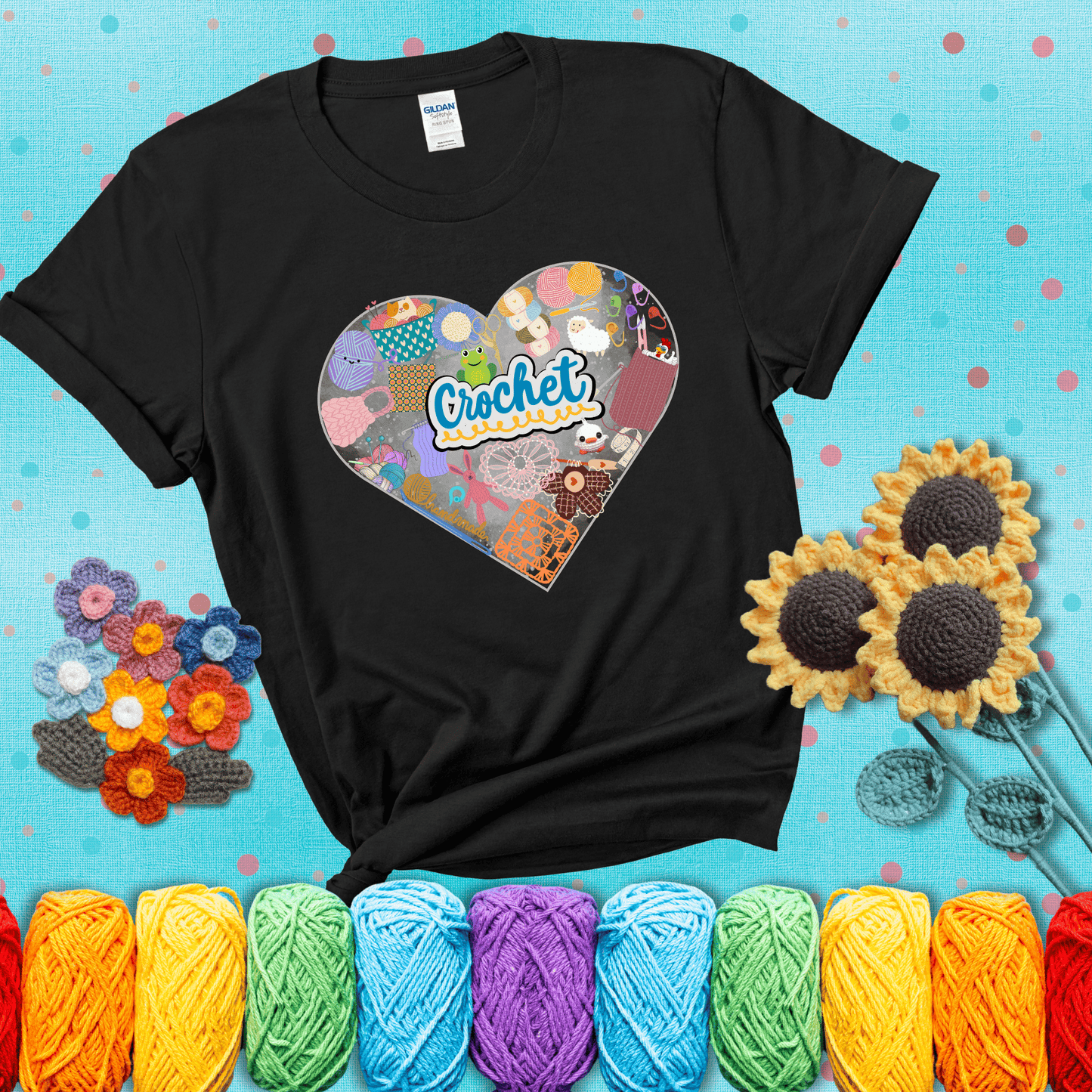 A heart filled with colorful crochet essentials including yarn, hooks, scissors, notions, and handmade items, with the word "Crochet" prominently in the center, showing a black tee with a teal sunflower background