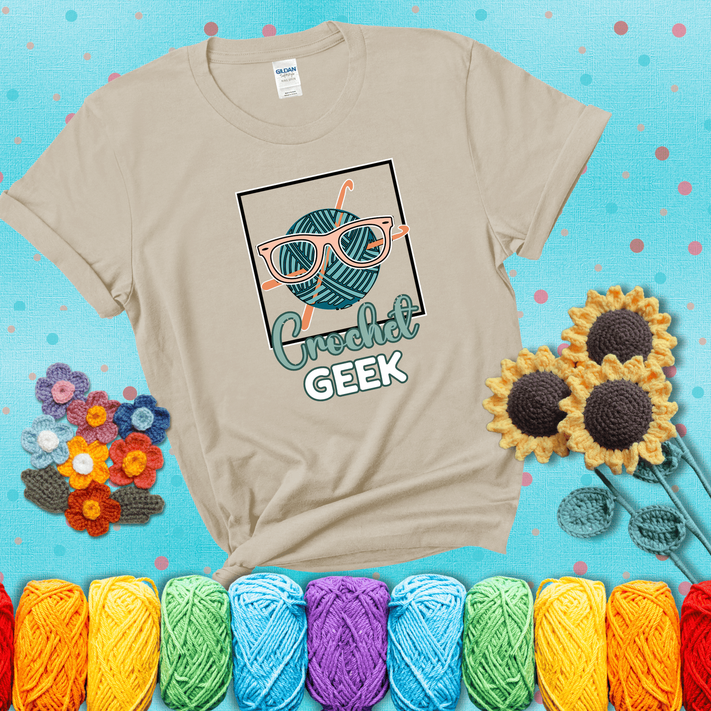A teal yarn ball with crisscrossed hooks wears oversized nerdy glasses with the phrase “Crochet Geek” in bold, fun text below, showing a beige tee with a teal sunflower background