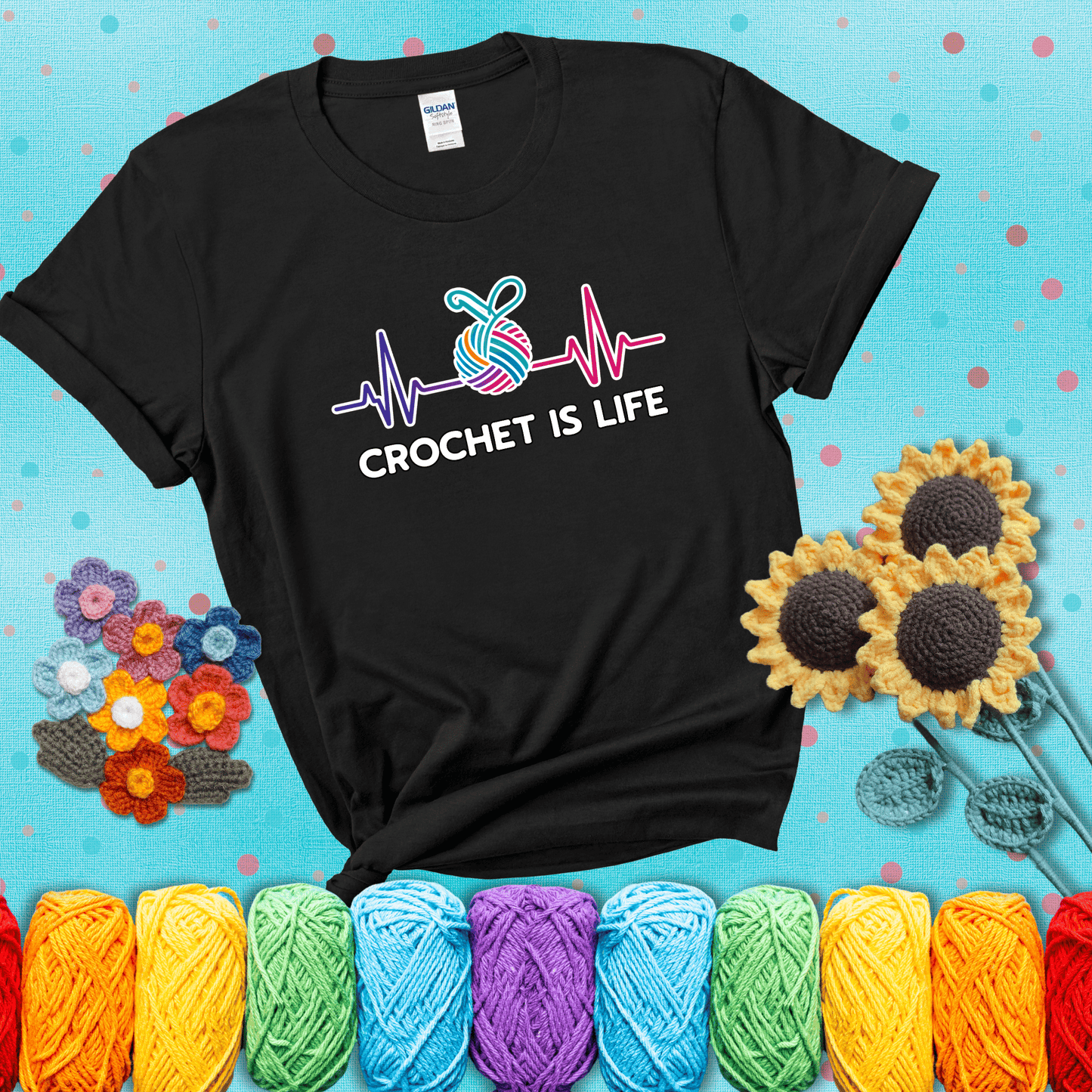 A heartbeat line with a colorful yarn ball and crochet hook in the center, with the words “Crochet is Life”, showing a black tee with a teal sunflower background