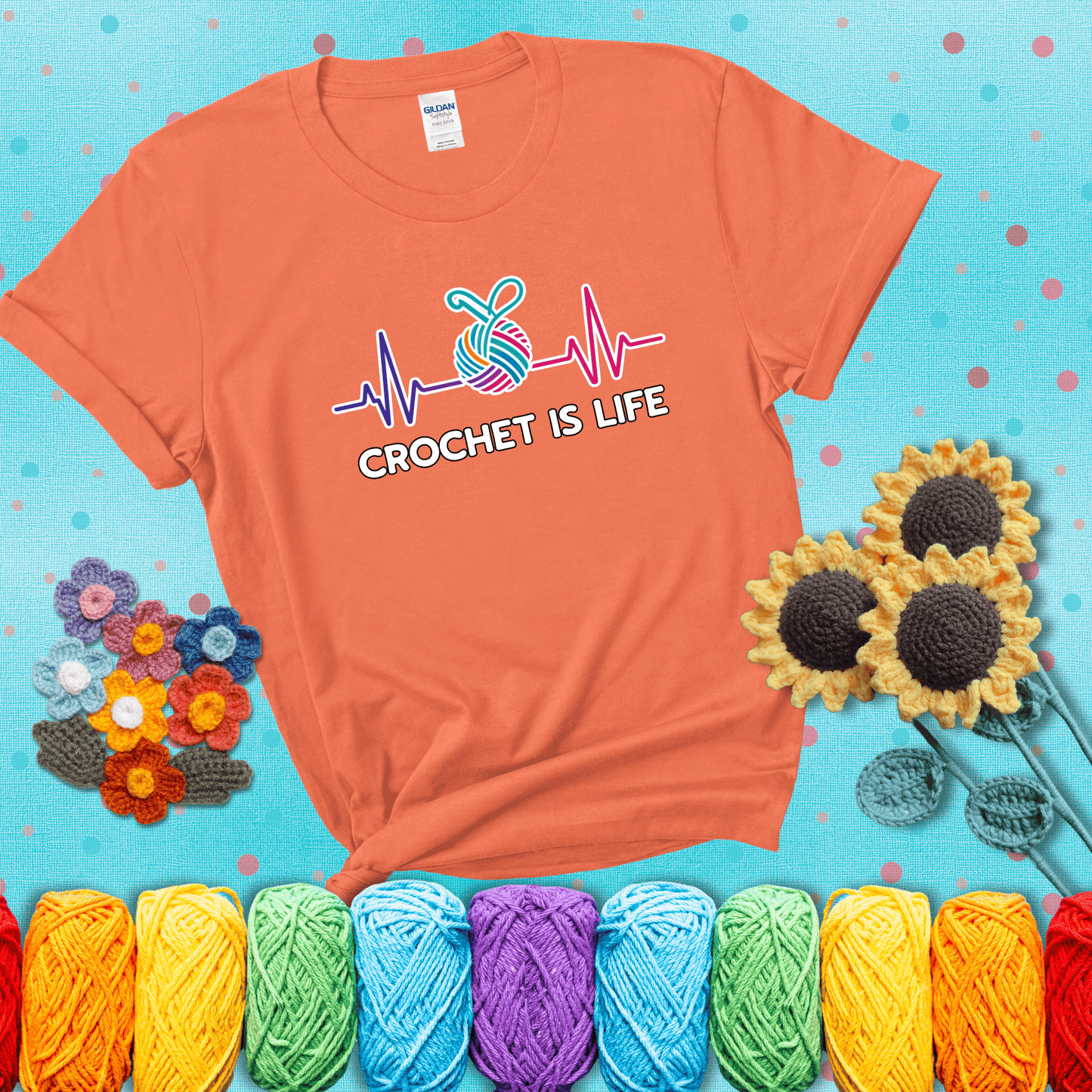 A heartbeat line with a colorful yarn ball and crochet hook in the center, with the words “Crochet is Life”, showing a light orange tee with a teal sunflower background