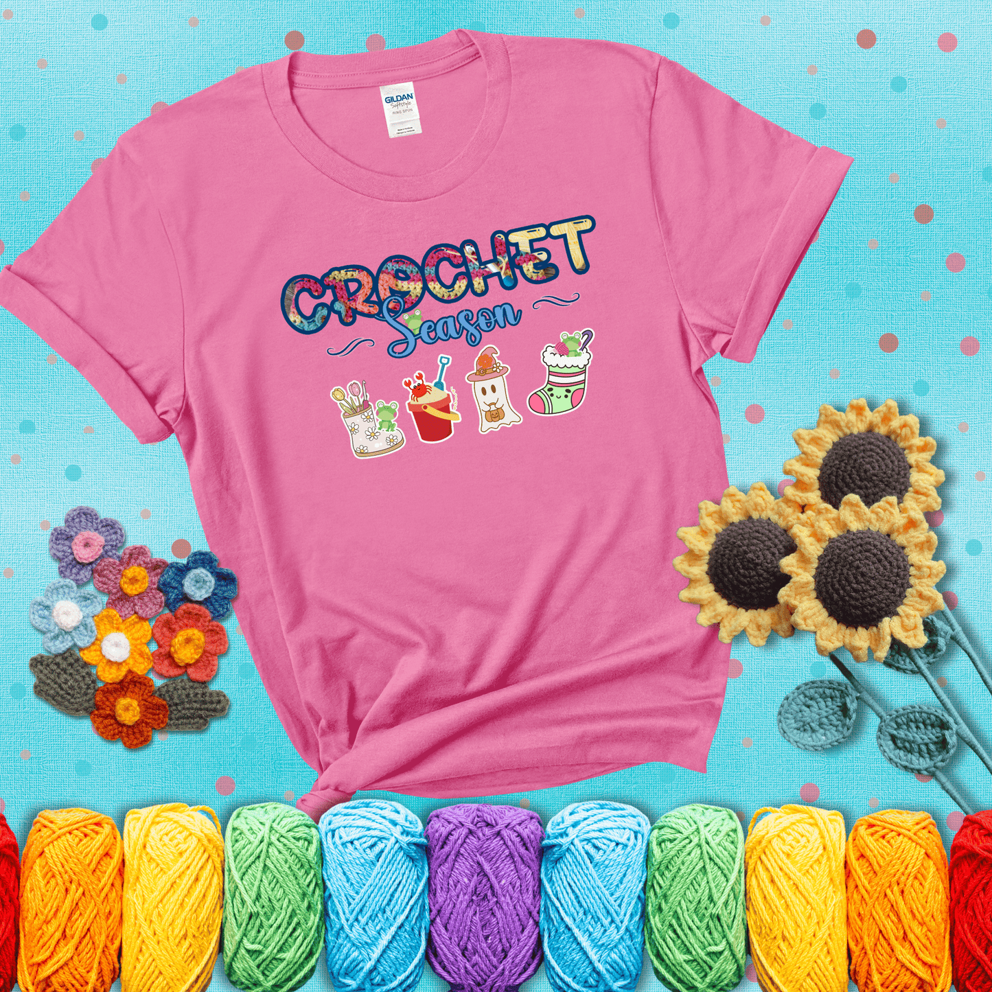 The words “Crochet Season” with cute seasonal icons below: a spring boot with hooks, summer bucket with crab, fall ghost with pumpkin hat, and winter stocking - all with tiny frogs; showing a pink tee with a teal sunflower background