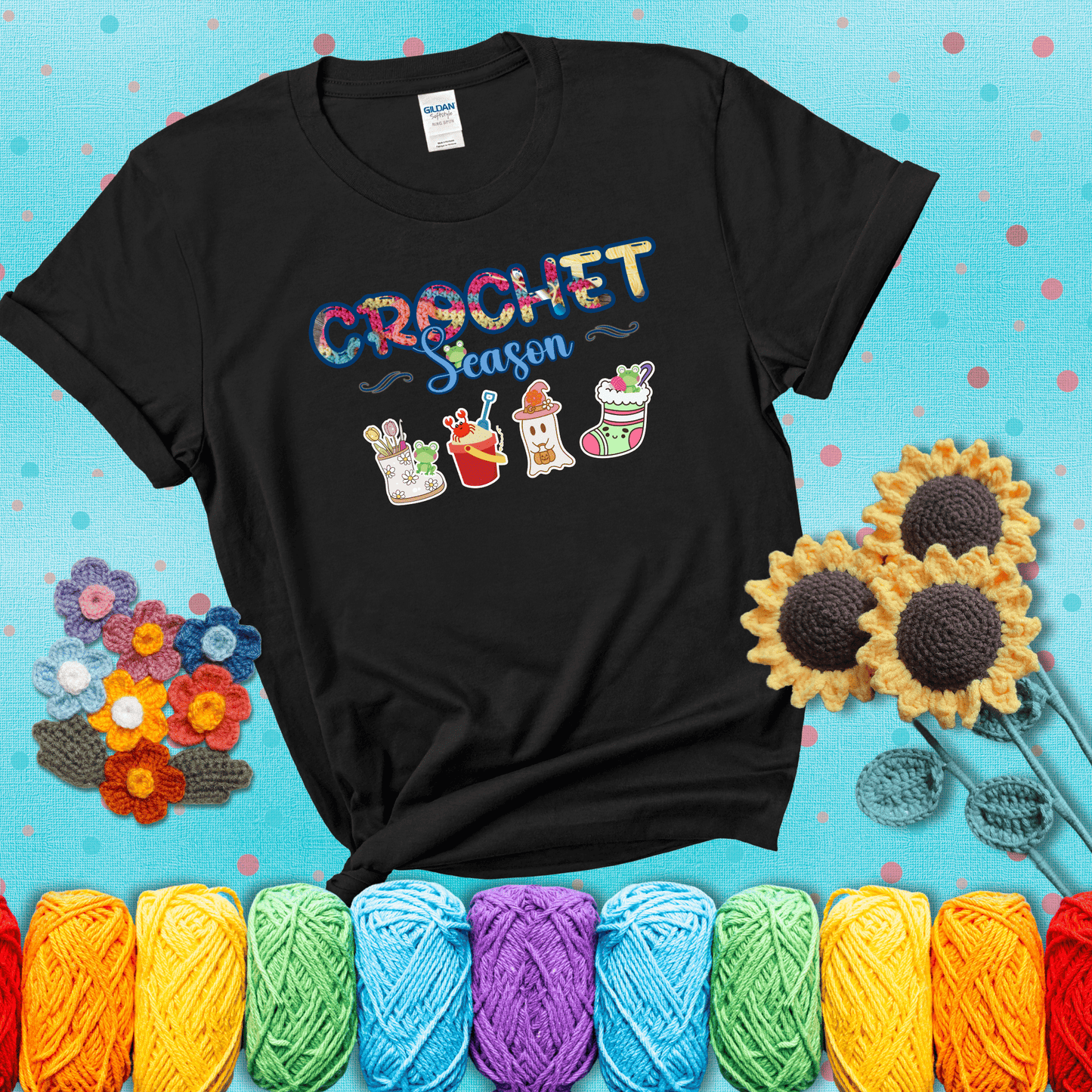 The words “Crochet Season” with cute seasonal icons below: a spring boot with hooks, summer bucket with crab, fall ghost with pumpkin hat, and winter stocking - all with tiny frogs; showing a black tee with a teal sunflower background
