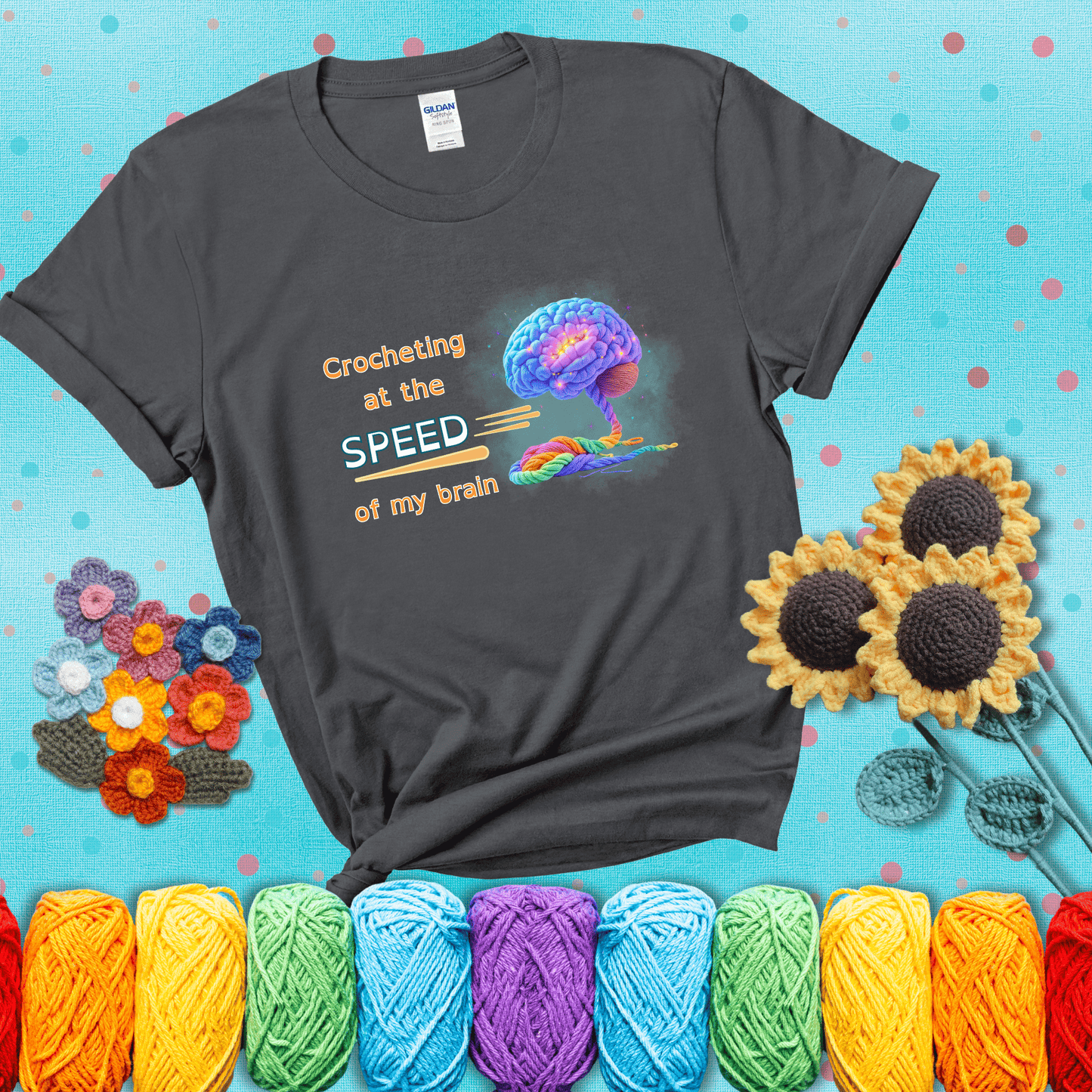 A glowing rainbow brain unravels into colorful yarn with the phrase “Crocheting at the speed of my brain;" showing a dark grey tee with a teal sunflower background