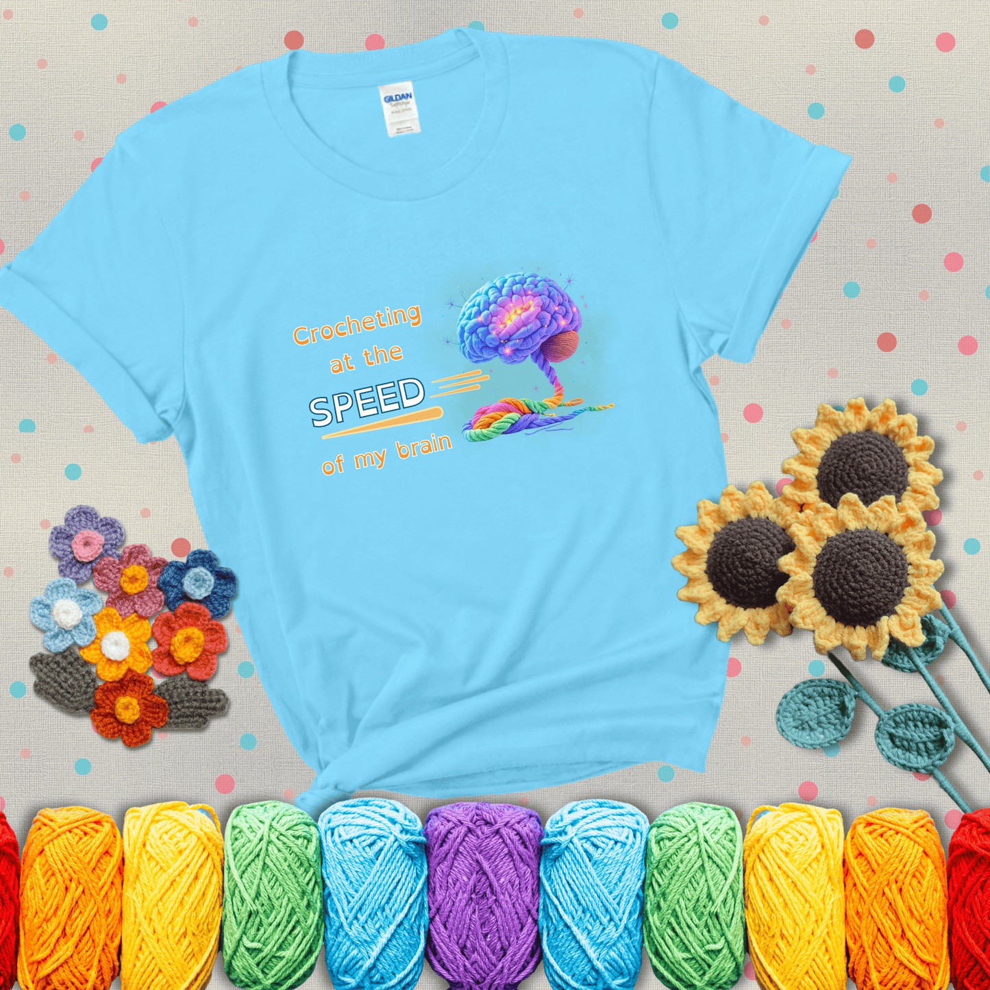 A glowing rainbow brain unravels into colorful yarn with the phrase “Crocheting at the speed of my brain;" showing a light blue tee with grey sunflower background