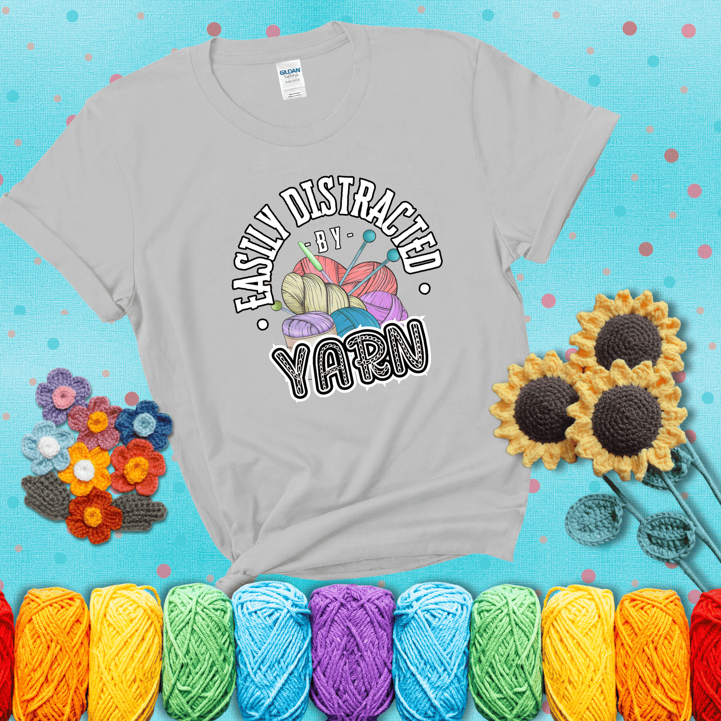 If yarn steals your focus every Design reads 'Easily Distracted By Yarn', perfect crochet gift for yarn lovers; showing a light grey tee with a teal sunflower background