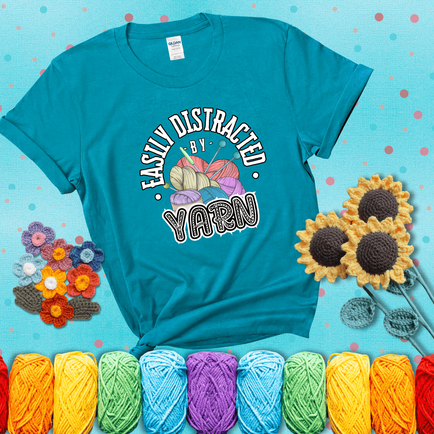 If yarn steals your focus every Design reads 'Easily Distracted By Yarn', perfect crochet gift for yarn lovers; showing a blue-green tee with a teal sunflower background