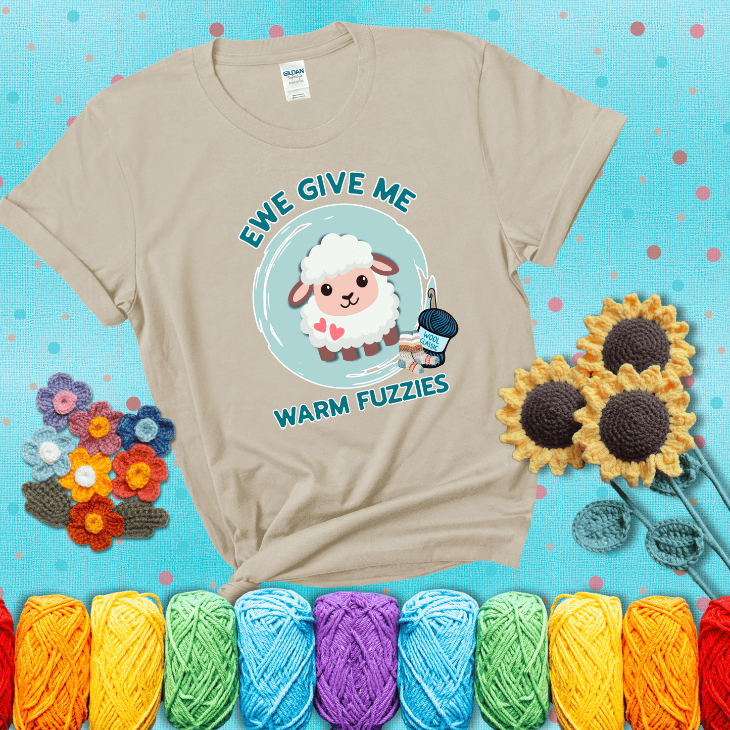 Cartoon sheep with pink hearts, wool socks, and yarn labeled “Wool Classic.” Text reads “Ewe Give Me Warm Fuzzies” showing a beige tee with a teal sunflower background