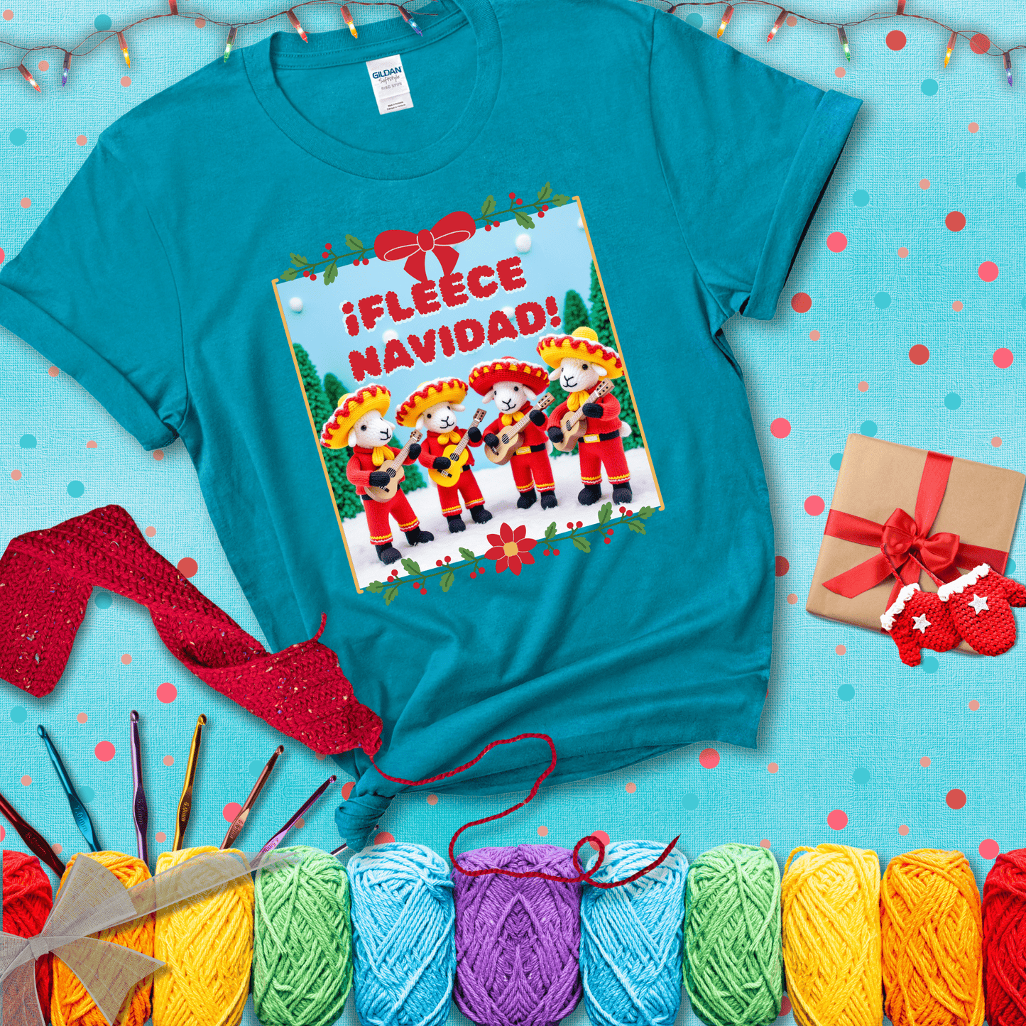 Four crocheted sheep dressed in red mariachi outfits with guitars, standing in a snowy scene under the phrase “¡Fleece Navidad!” showing a blue-green tee with a festive Christmas background