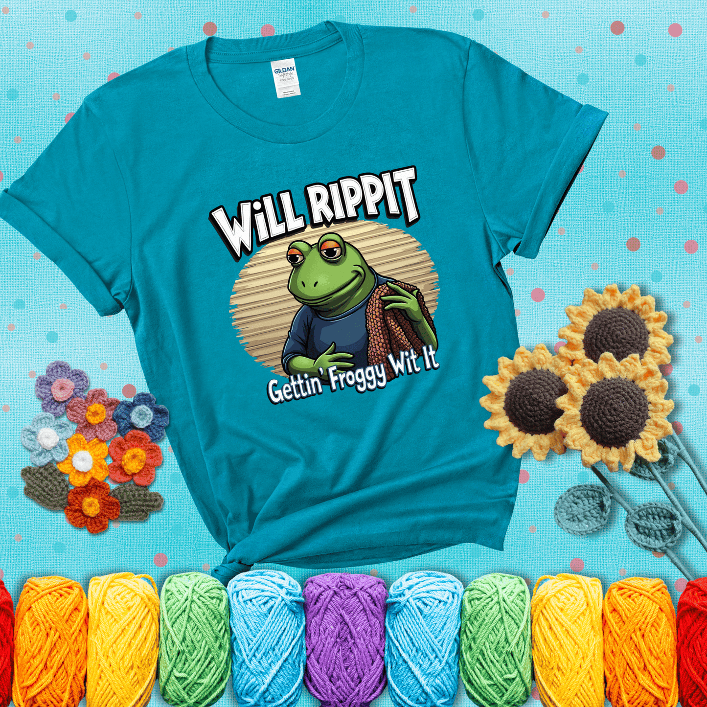 Cool frog with sunglasses, surrounded by yarn and hooks. Text reads: “Gettin’ Froggy Wit It.” A hip and humorous crochet tee for yarn lovers with rhythm, showing a blue-green tee with a teal sunflower background