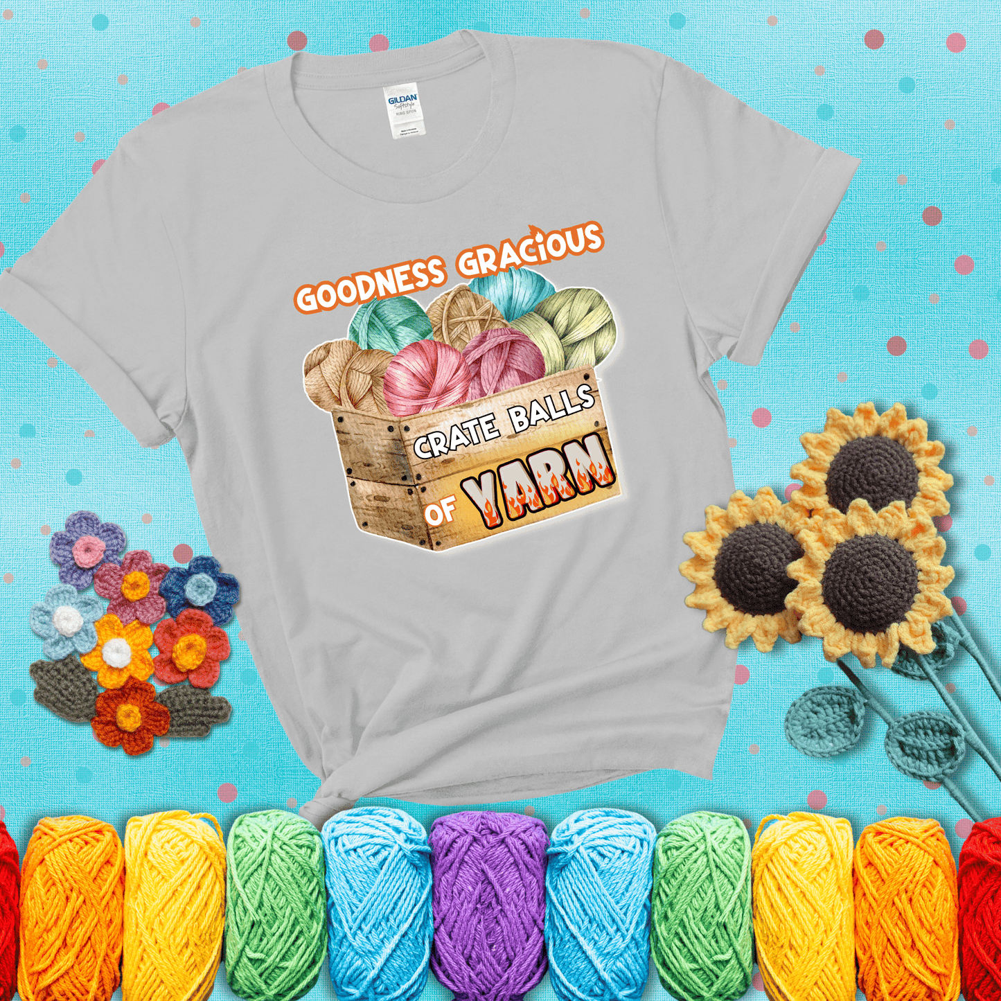Wooden crate filled with colorful yarn balls and bold text “Goodness Gracious, Crate Balls of Yarn” with flame effects, a funny gift for crocheters showing a light grey tee with a teal sunflower background