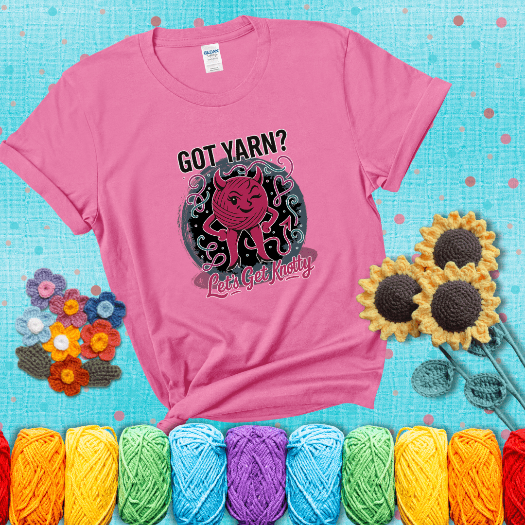 A cheeky pink yarn ball with devil horns, arms, and legs winks under the text “Got Yarn? Let’s Get Knotty,” showing a pink tee with a teal sunflower background