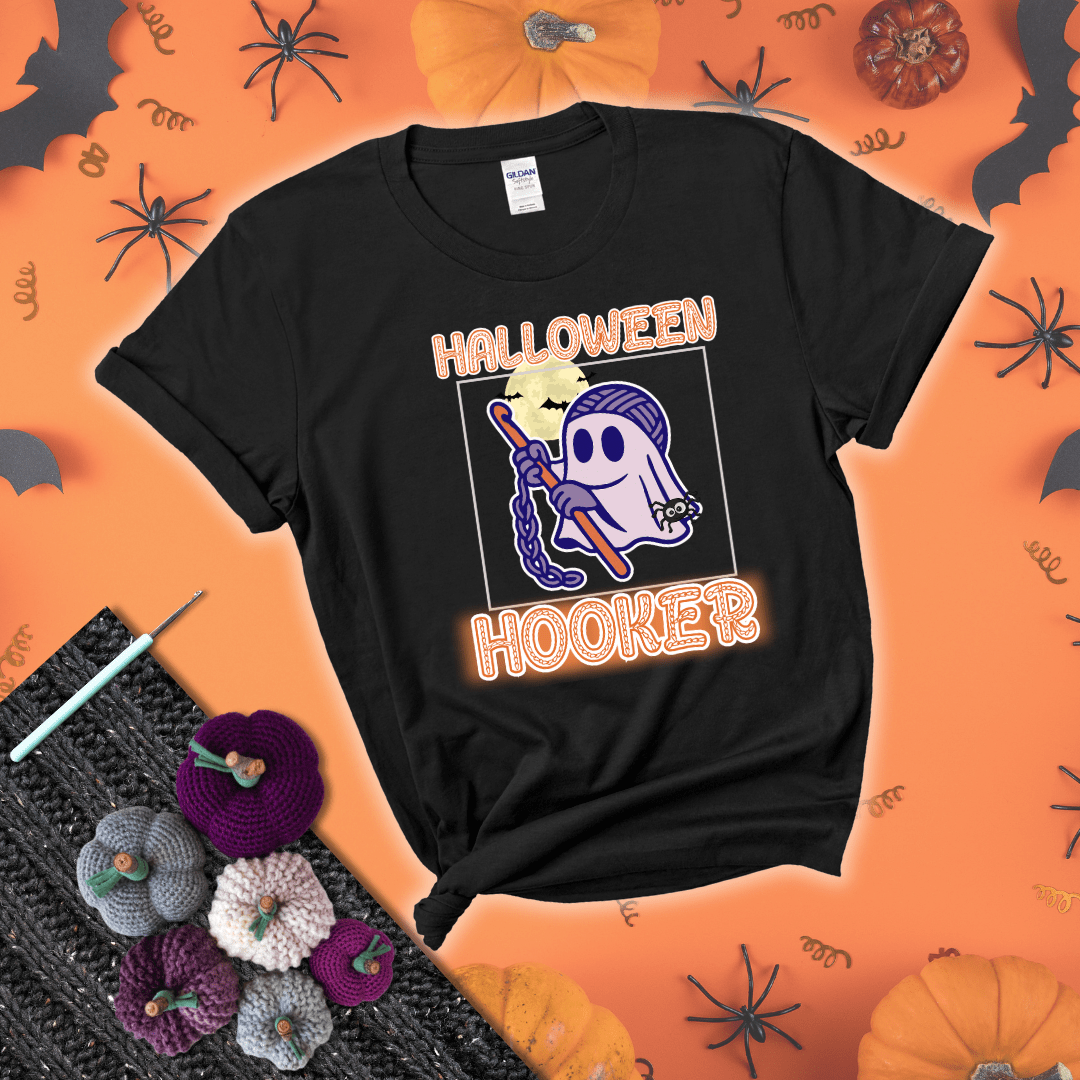 Cartoon ghost crocheter with a yarn ball head, crochet hook, bats, and text “Halloween Hooker,” a fun spooky tee for yarn lovers showing a black tee with a festive Halloween background