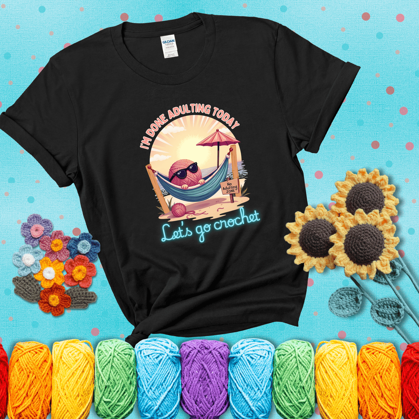 A chill yarn ball wearing sunglasses lounges in a hammock on a beach under the sun with the phrase “I’m done adulting today – Let’s go crochet,” showing a black tee with a teal sunflower background
