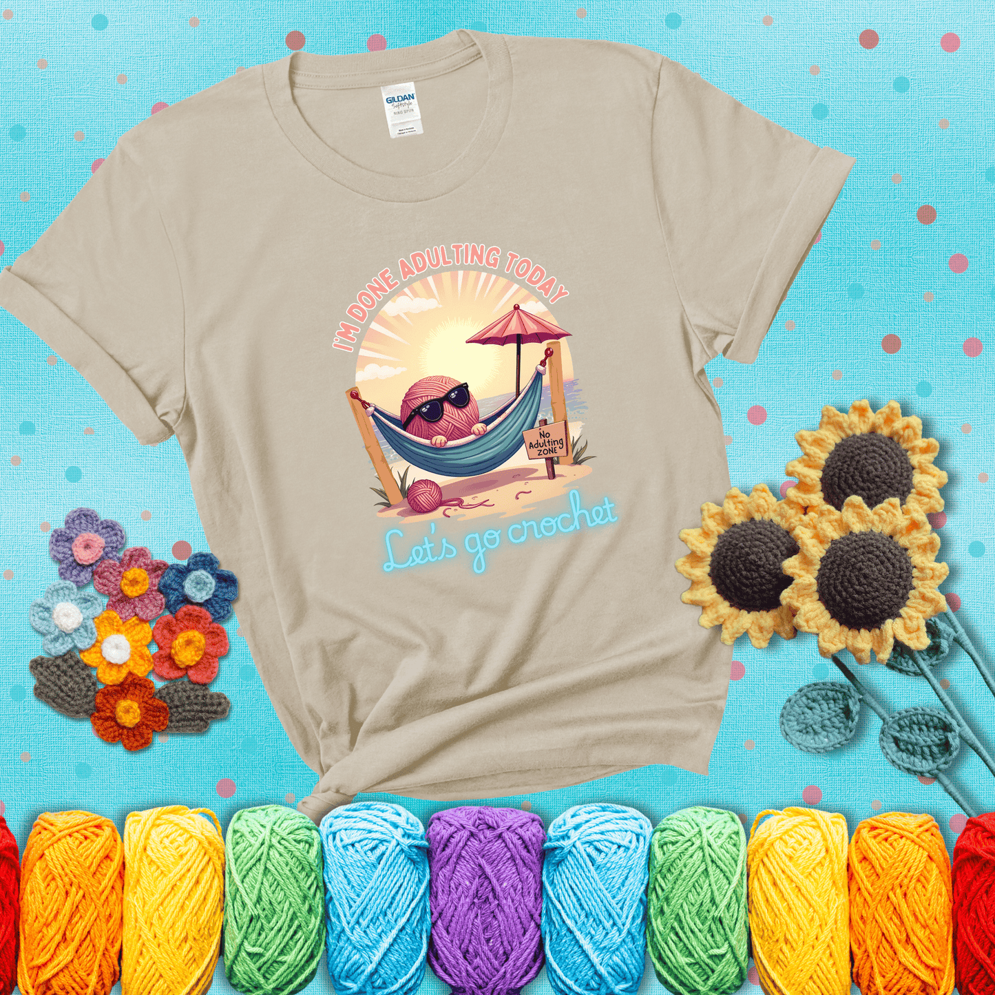 A chill yarn ball wearing sunglasses lounges in a hammock on a beach under the sun with the phrase “I’m done adulting today – Let’s go crochet,” showing a beige tee with a teal sunflower background
