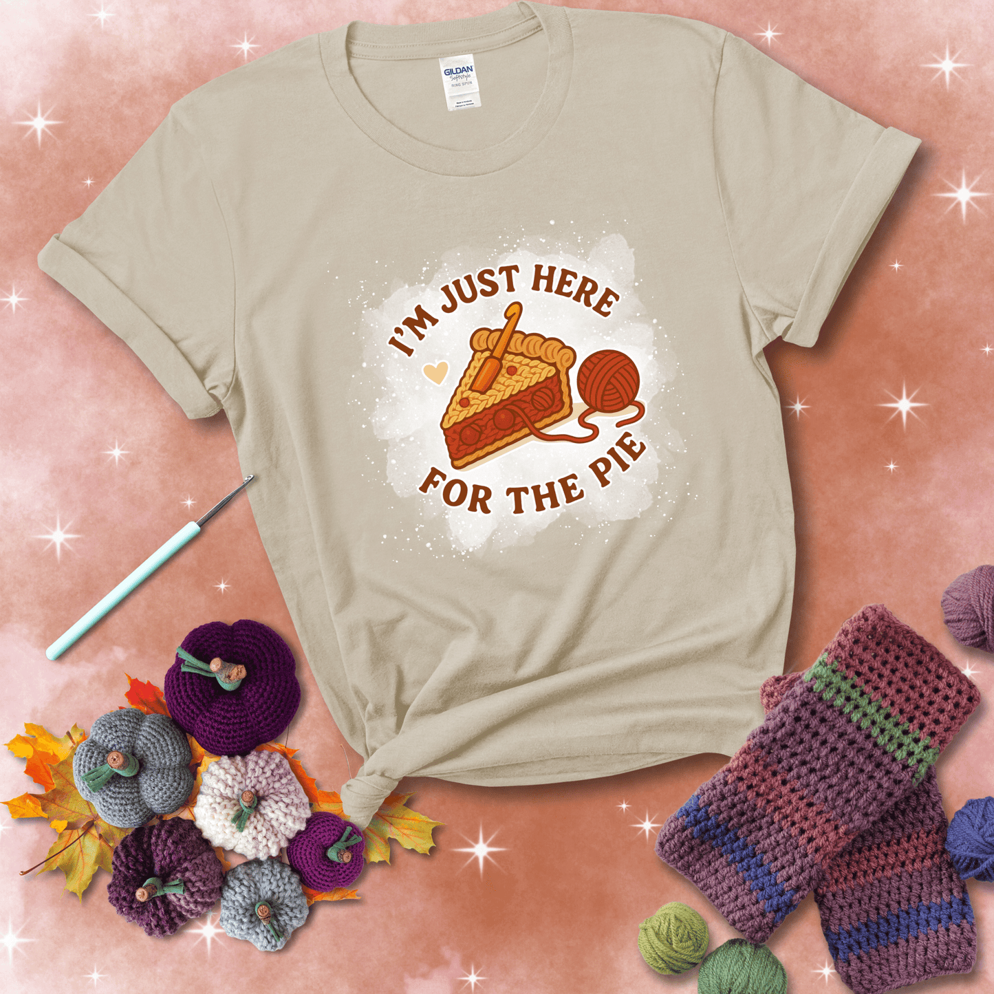 A slice of cherry pie with a crochet hook tucked in the filling and yarn trailing out, blending baking with crochet fun, showing a beige tee with a festive Fall background