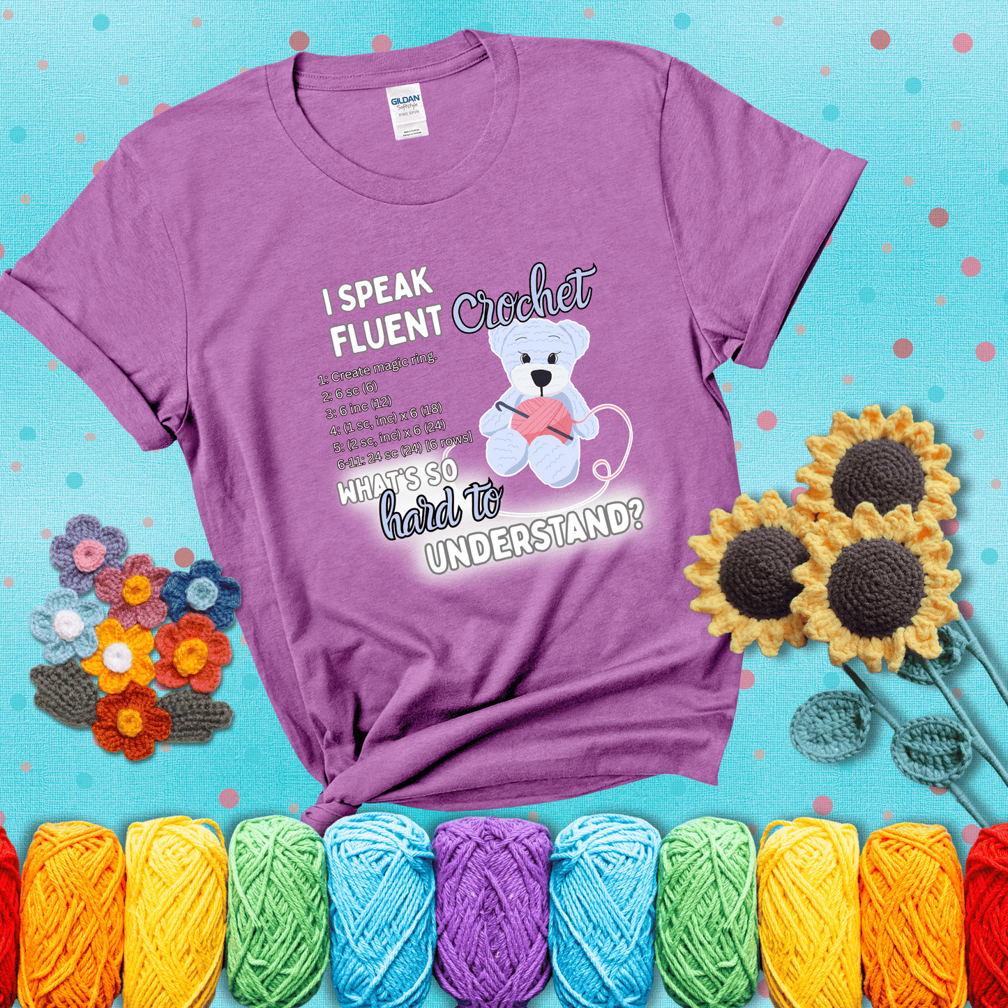 A cute crochet bear holding a yarn ball, surrounded by a short crochet pattern. The phrase reads “I Speak Fluent Crochet – What’s so hard to understand?” showing a light purple tee with a teal sunflower background