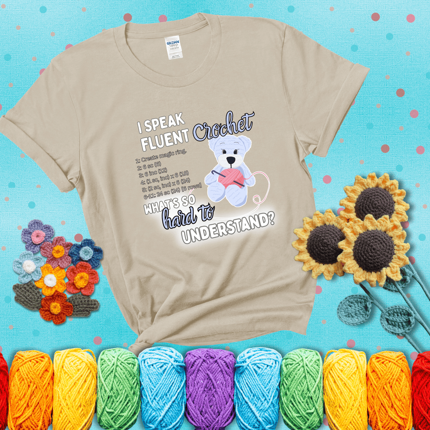 A cute crochet bear holding a yarn ball, surrounded by a short crochet pattern. The phrase reads “I Speak Fluent Crochet – What’s so hard to understand?” showing a beige tee with a teal sunflower background