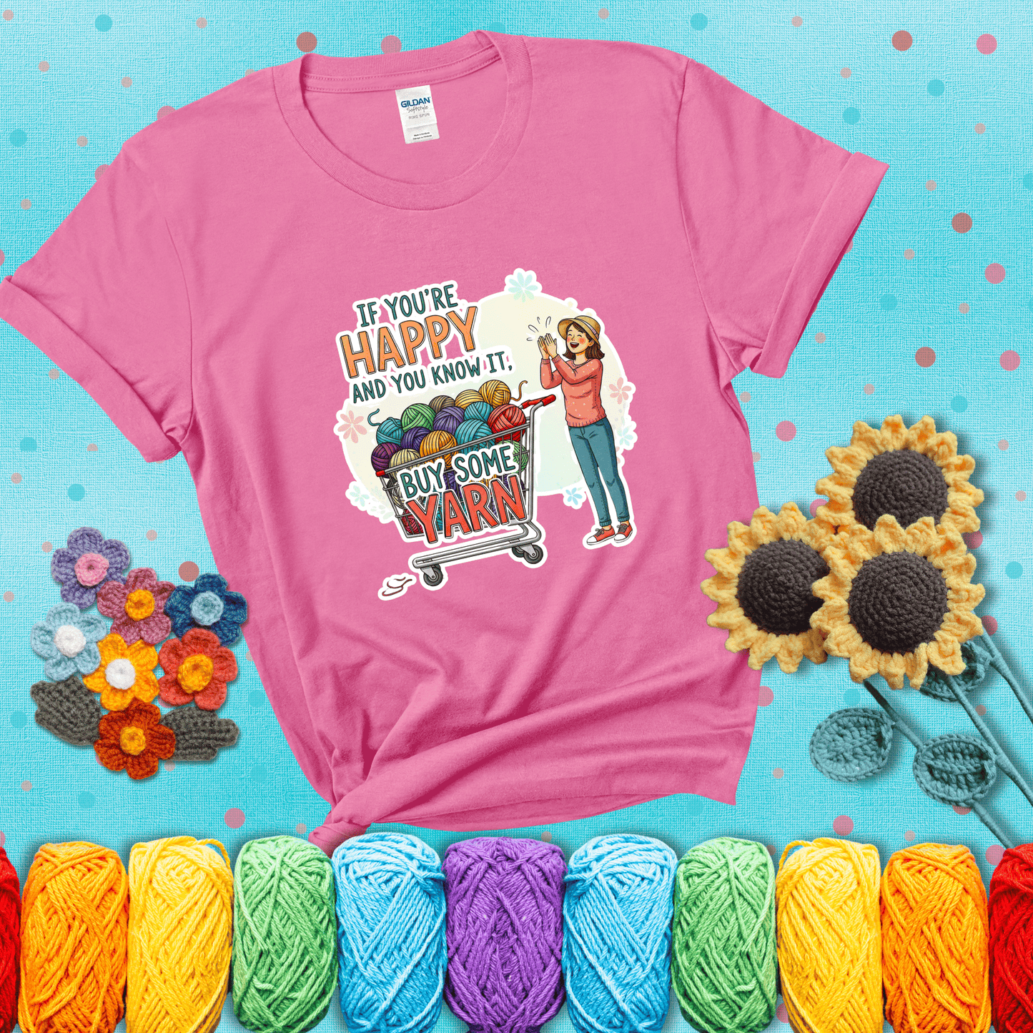Woman clapping beside a shopping cart overflowing with colorful yarn balls, styled with cheerful pastel accents and bold playful lettering showing a pink tee with a teal sunflower background
